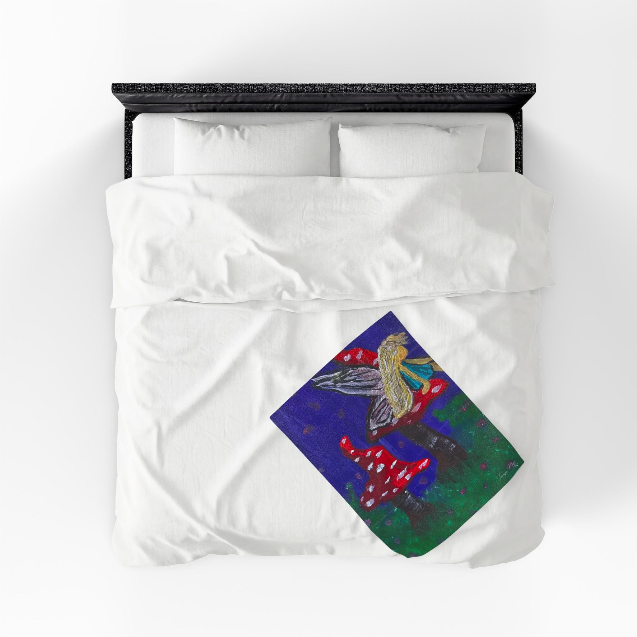 White plush throw blanket with fairy and red toadstool graphic, top view on bed
