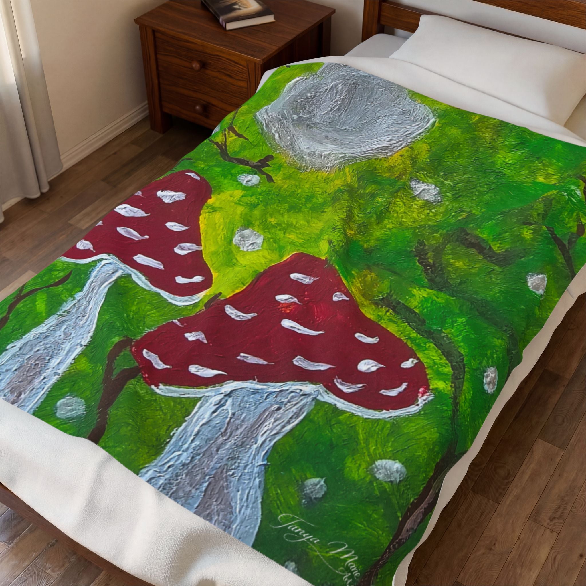 Plush velveteen blanket with green forest art, red spotted mushrooms, and gray stone