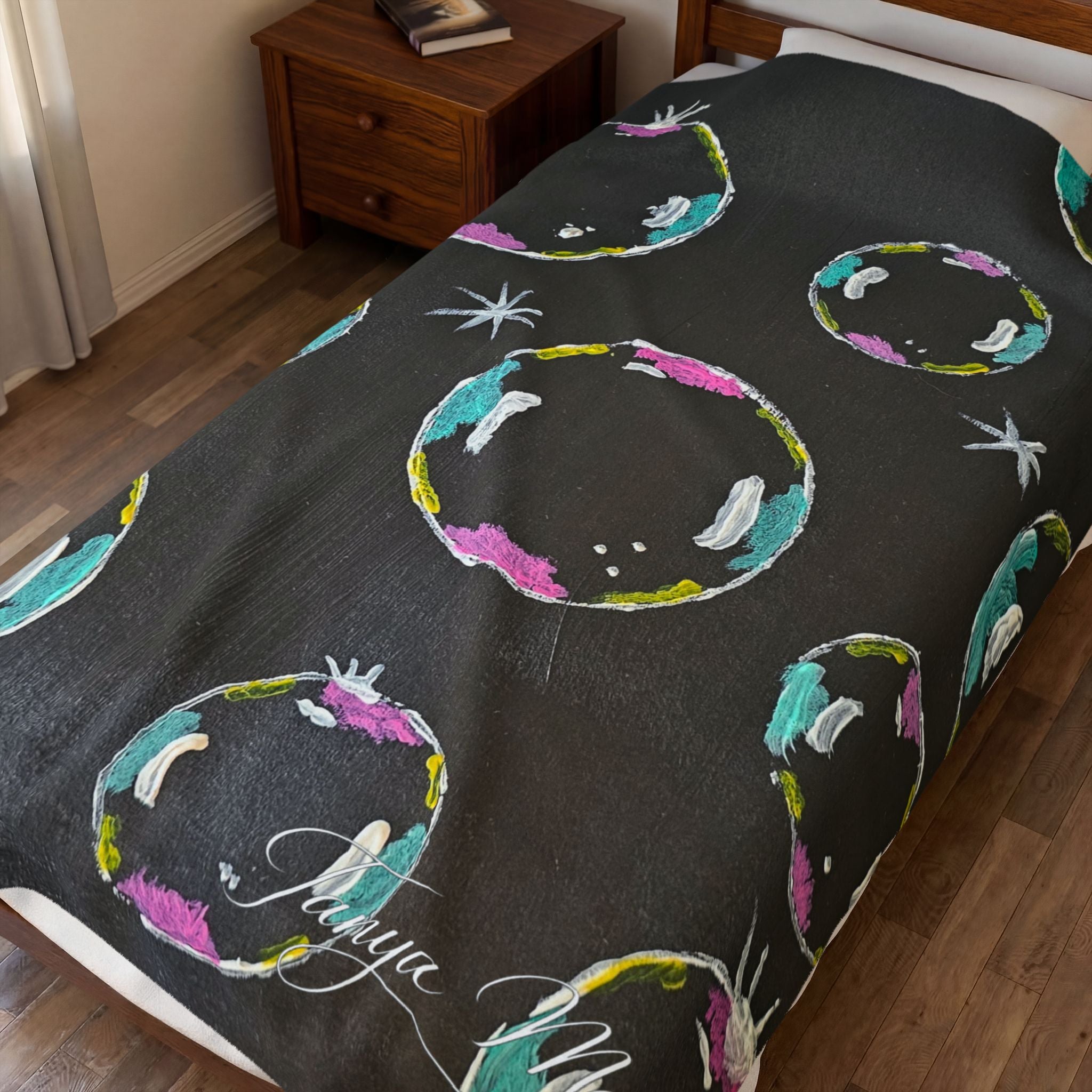 Black plush throw blanket close-up with colorful bubble rings and star shapes
