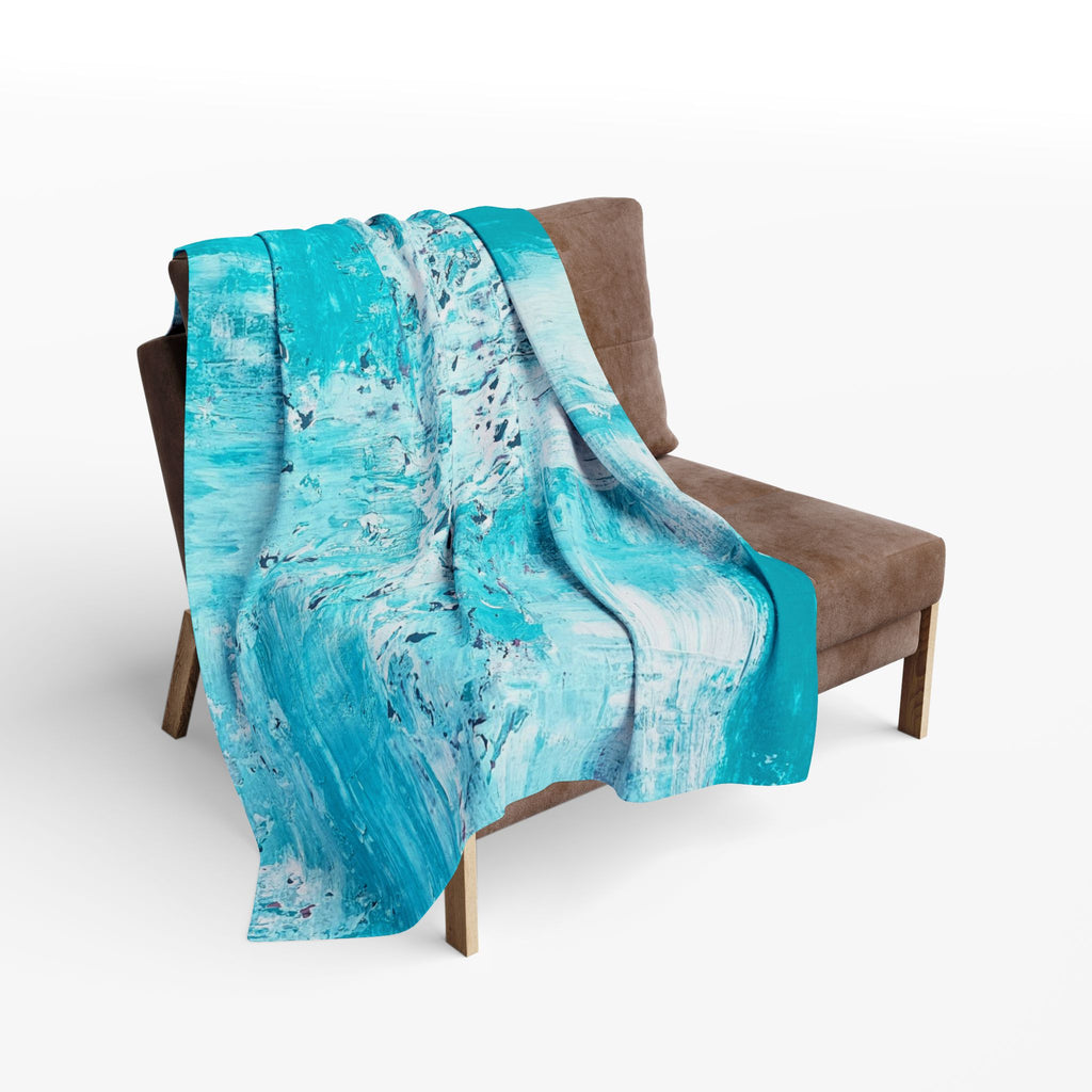 Turquoise abstract fleece blanket covering an armchair, draped on seat and back.