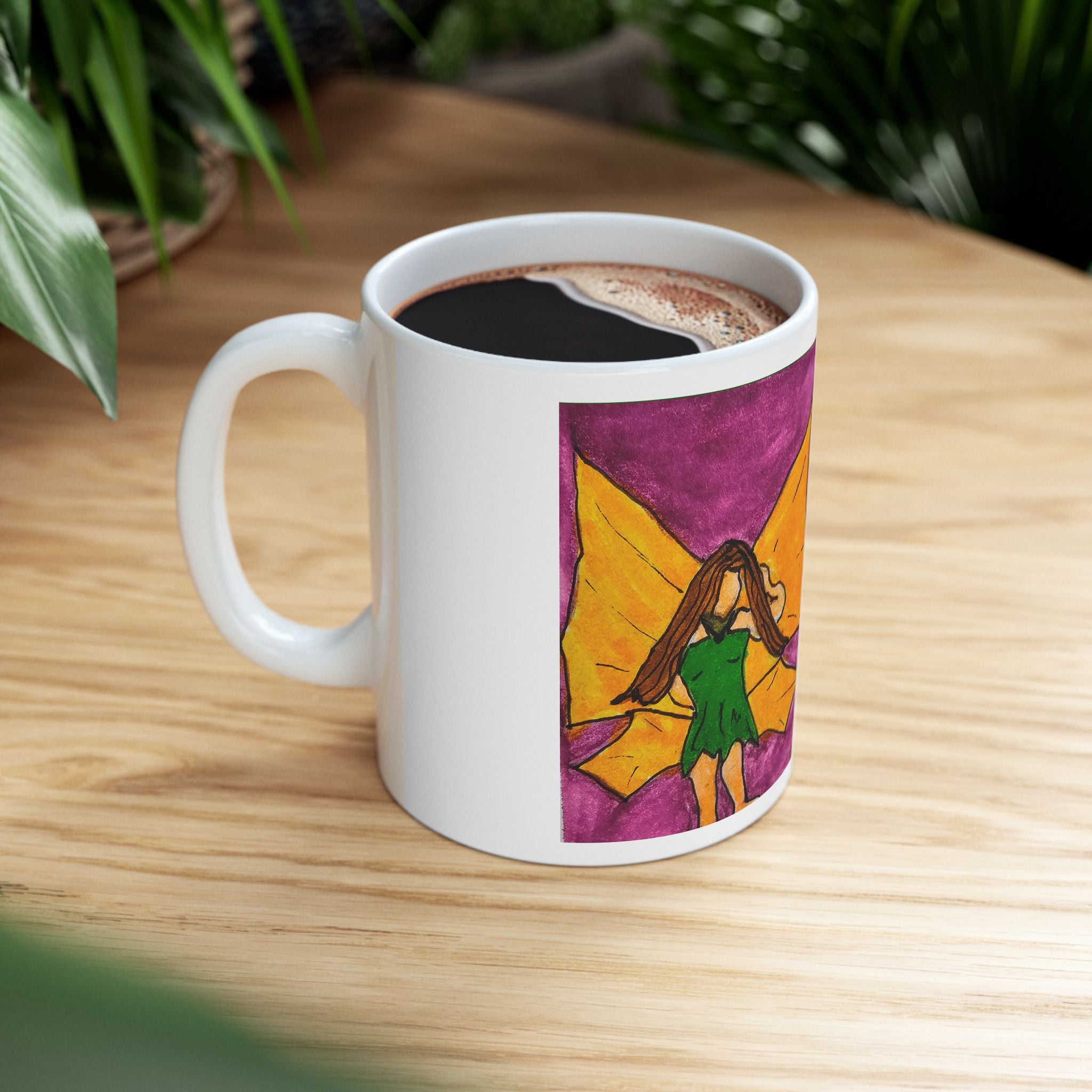 White ceramic mug on a wooden table with hot drink; side shows fairy wing watercolor art.