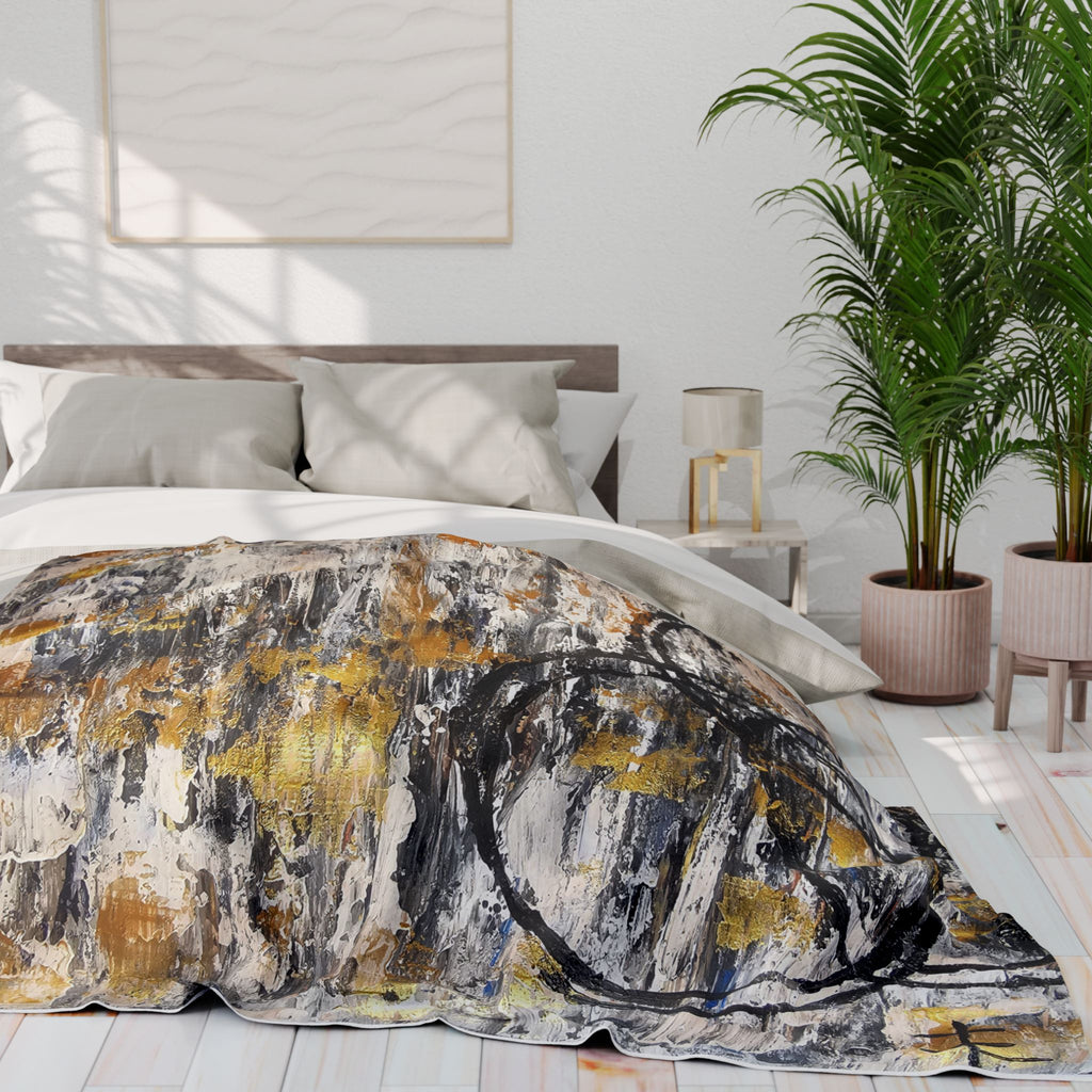 Abstract fleece blanket draped over bed, featuring gold dashes and dark circular marks