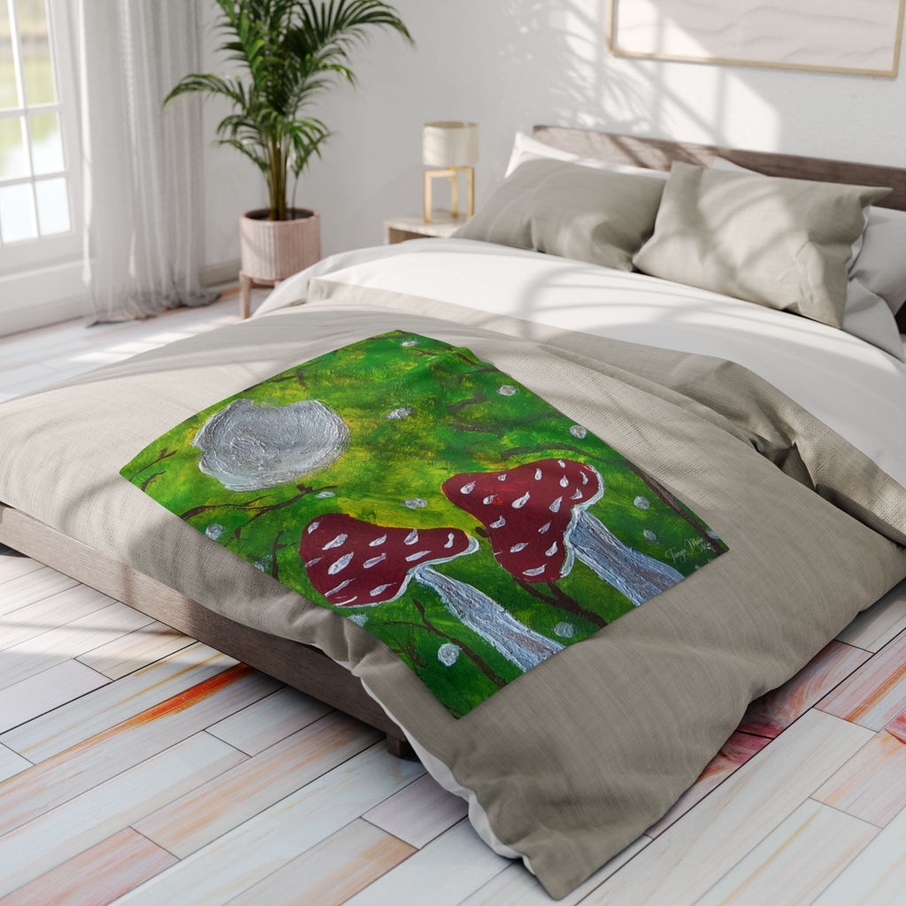 Fleece blanket on bed with green forest print, gray moon, and red mushrooms