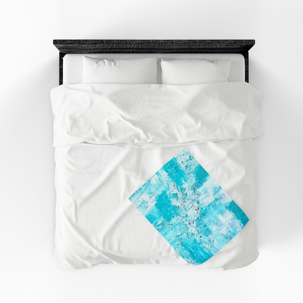 Turquoise abstract plush blanket with blue diamond graphic on white bedding, centered