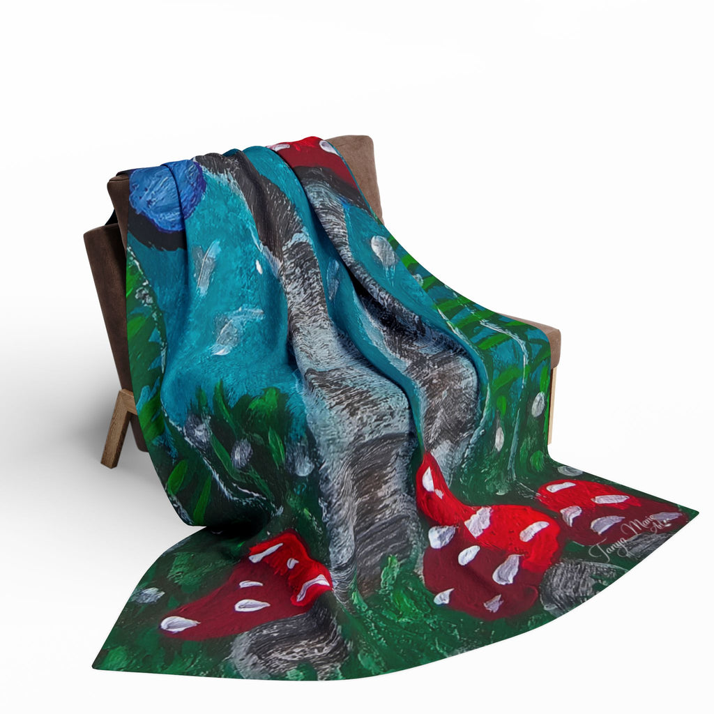 Fleece blanket tossed over furniture, showing red mushrooms on teal, green, and gray forest scene