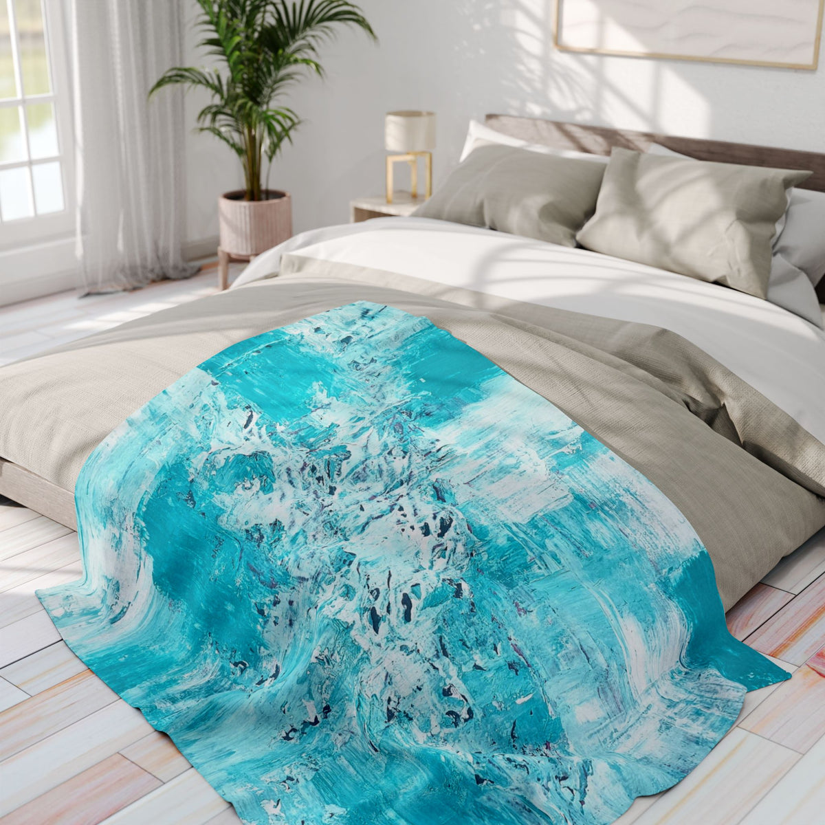 Turquoise abstract fleece blanket laid across a bed, bold blue-white pattern.