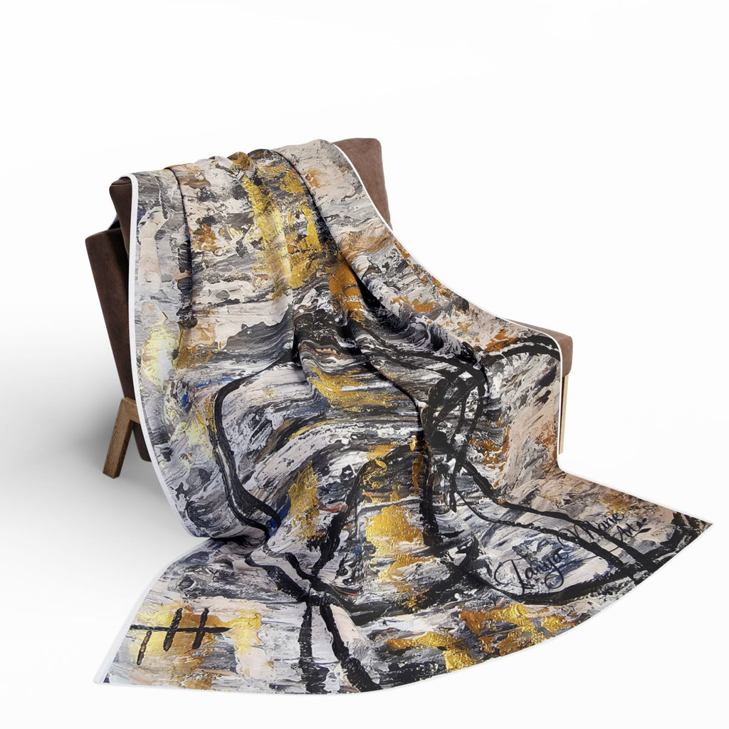 Fleece throw draped on chair seat and arm, abstract grey, black, and gold design
