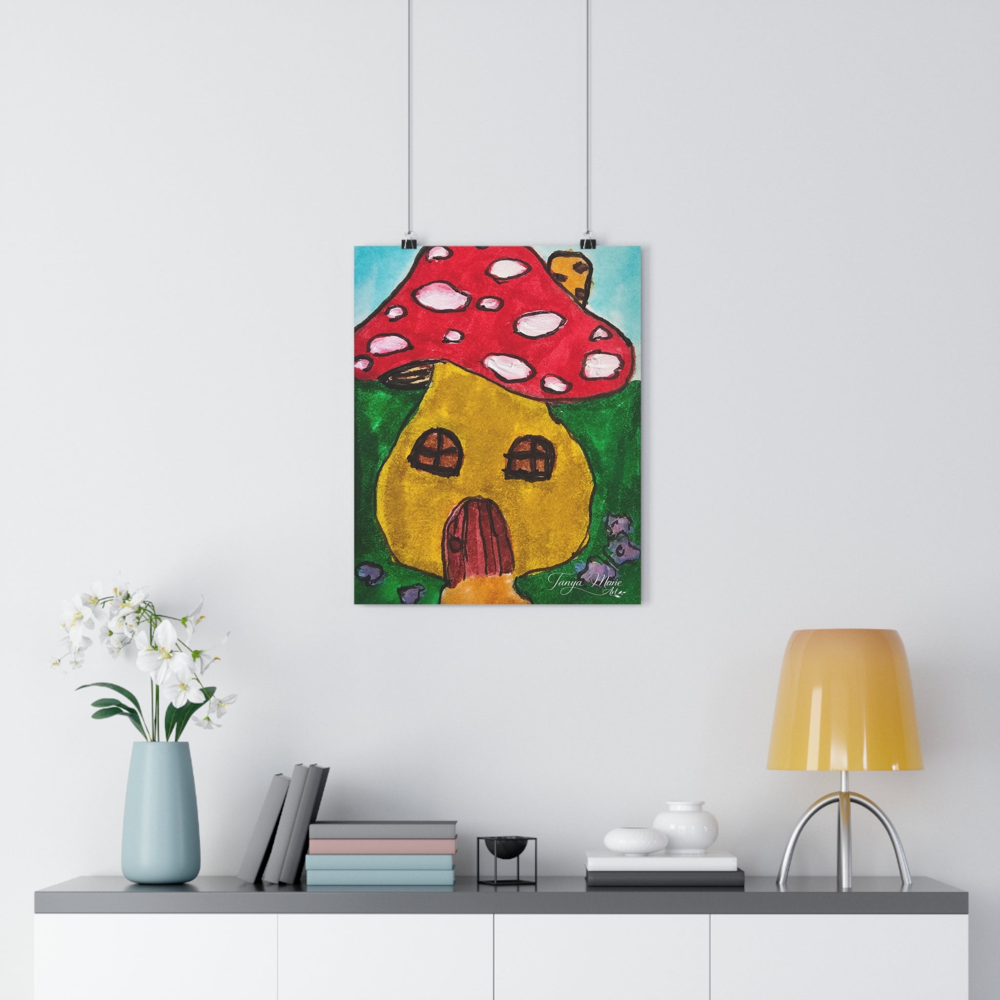 Hanging mushroom cottage art print with red cap and yellow house doorway, framed by cords