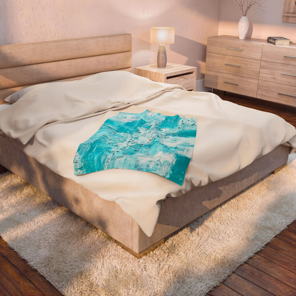 Turquoise abstract plush throw blanket on bed, draped over white sheets