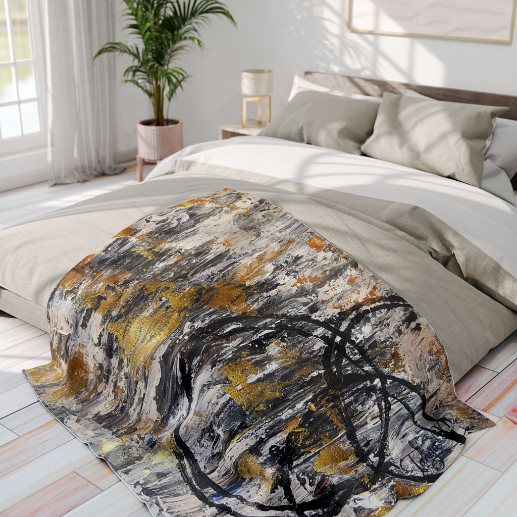 Abstract fleece throw blanket with circular black lines and gold accents on a bed