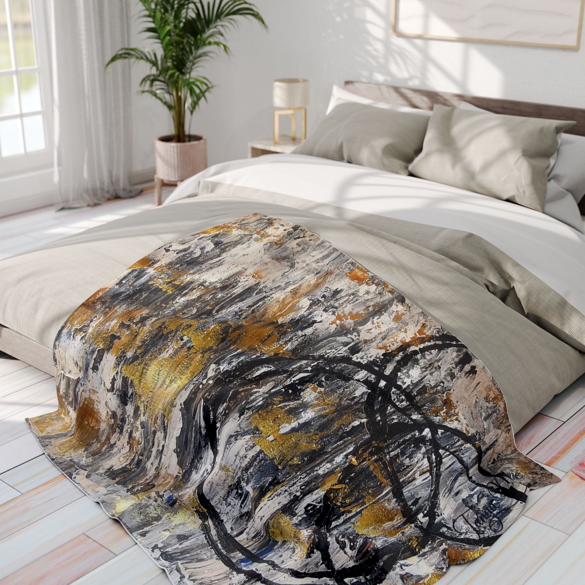 Abstract fleece throw blanket with circular black lines and gold accents on a bed