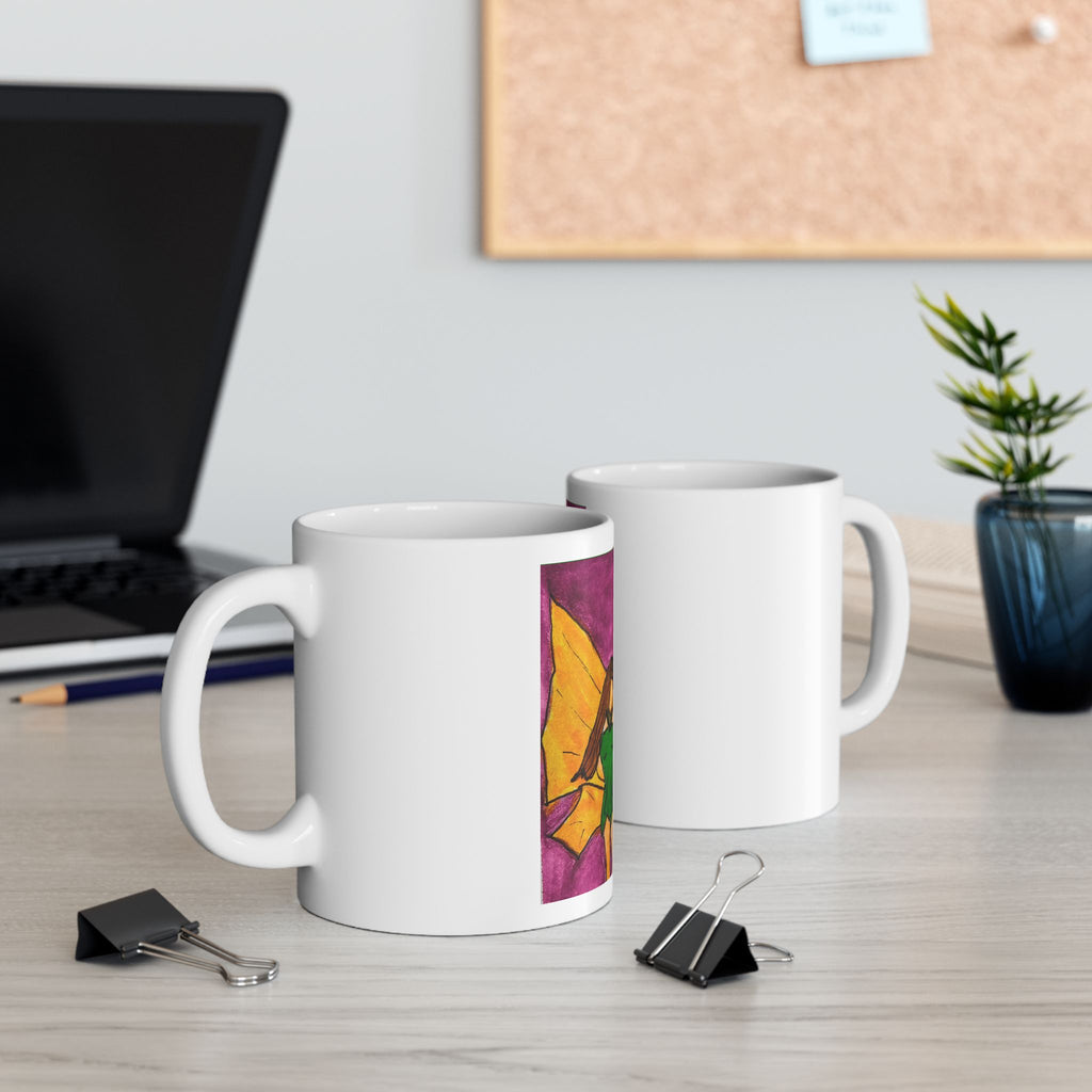Two white ceramic mugs on a desk, one showing a colorful fairy wing watercolor panel.