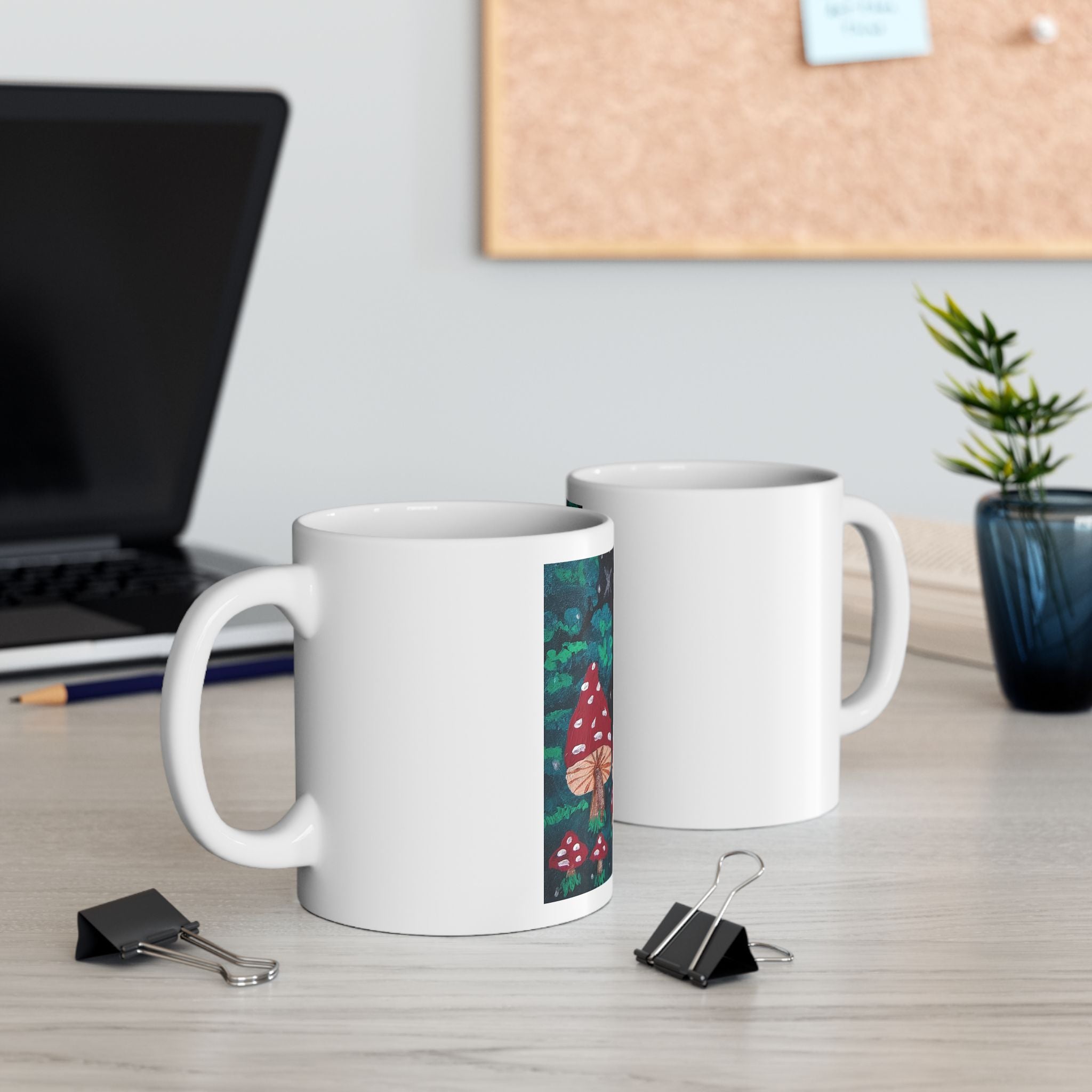 Two white ceramic coffee mugs, one with red toadstool forest design on the side