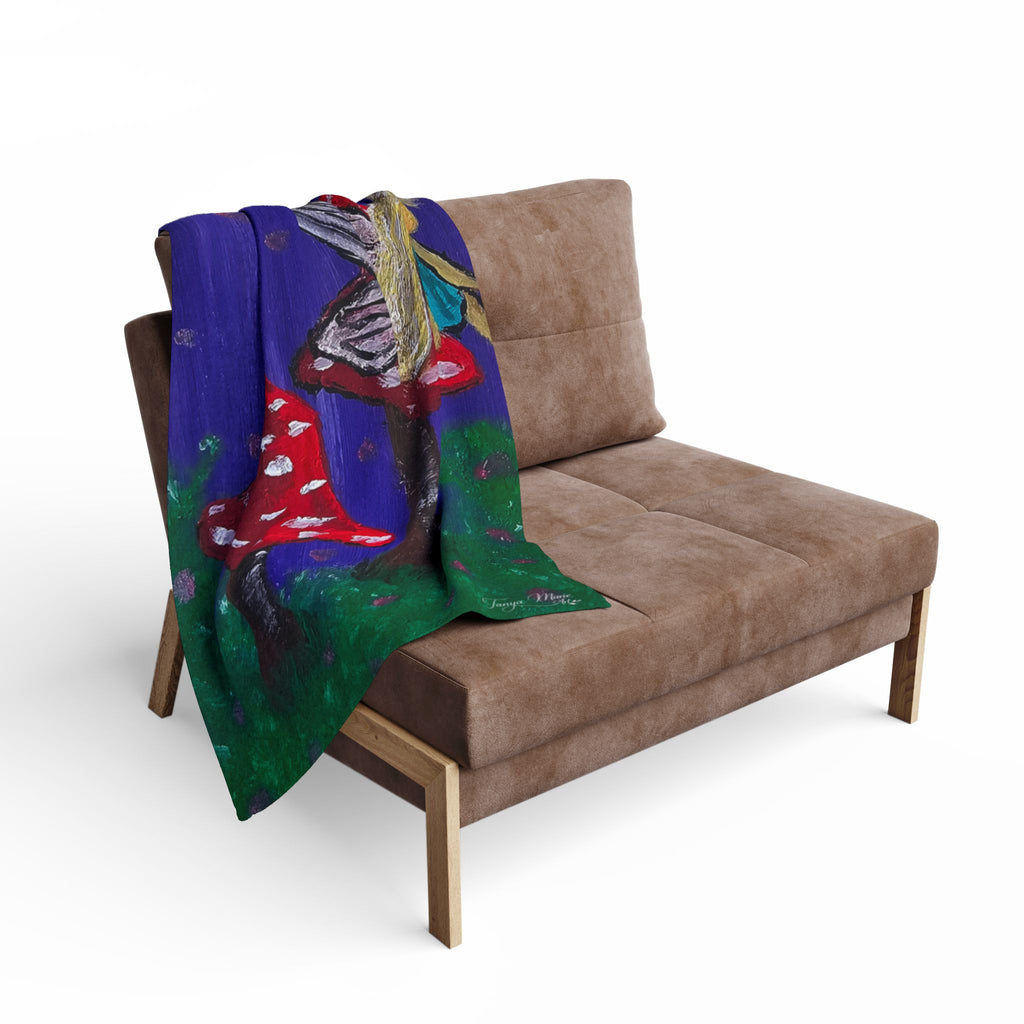 Fleece throw draped over couch with blue fairy-and-mushroom artwork in red and green