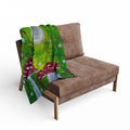 Fleece blanket with green mushroom scene and gray moon, draped over a brown chair