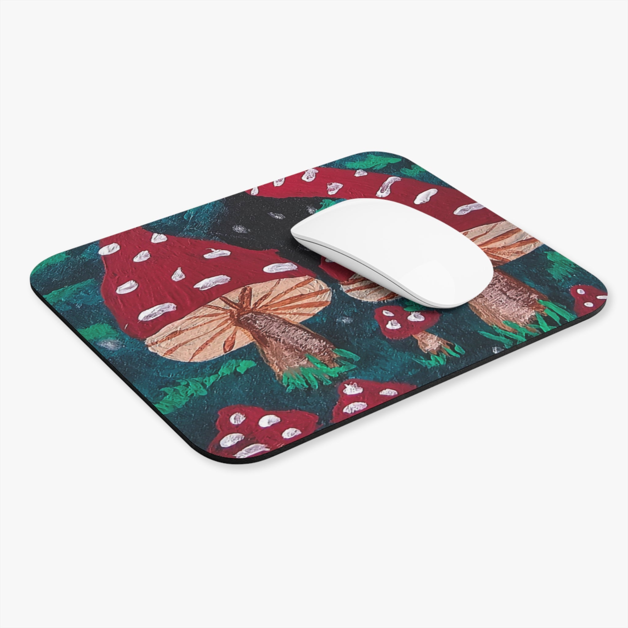 Rounded rectangle mushroom mouse pad with red toadstools and green accents; white mouse on top