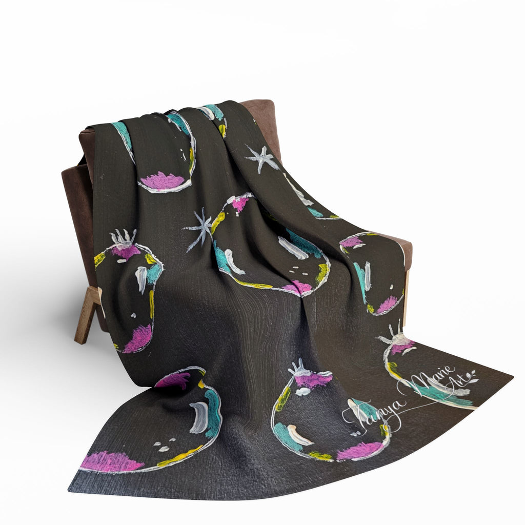 Black fleece throw blanket draped, colorful bubble and star print.