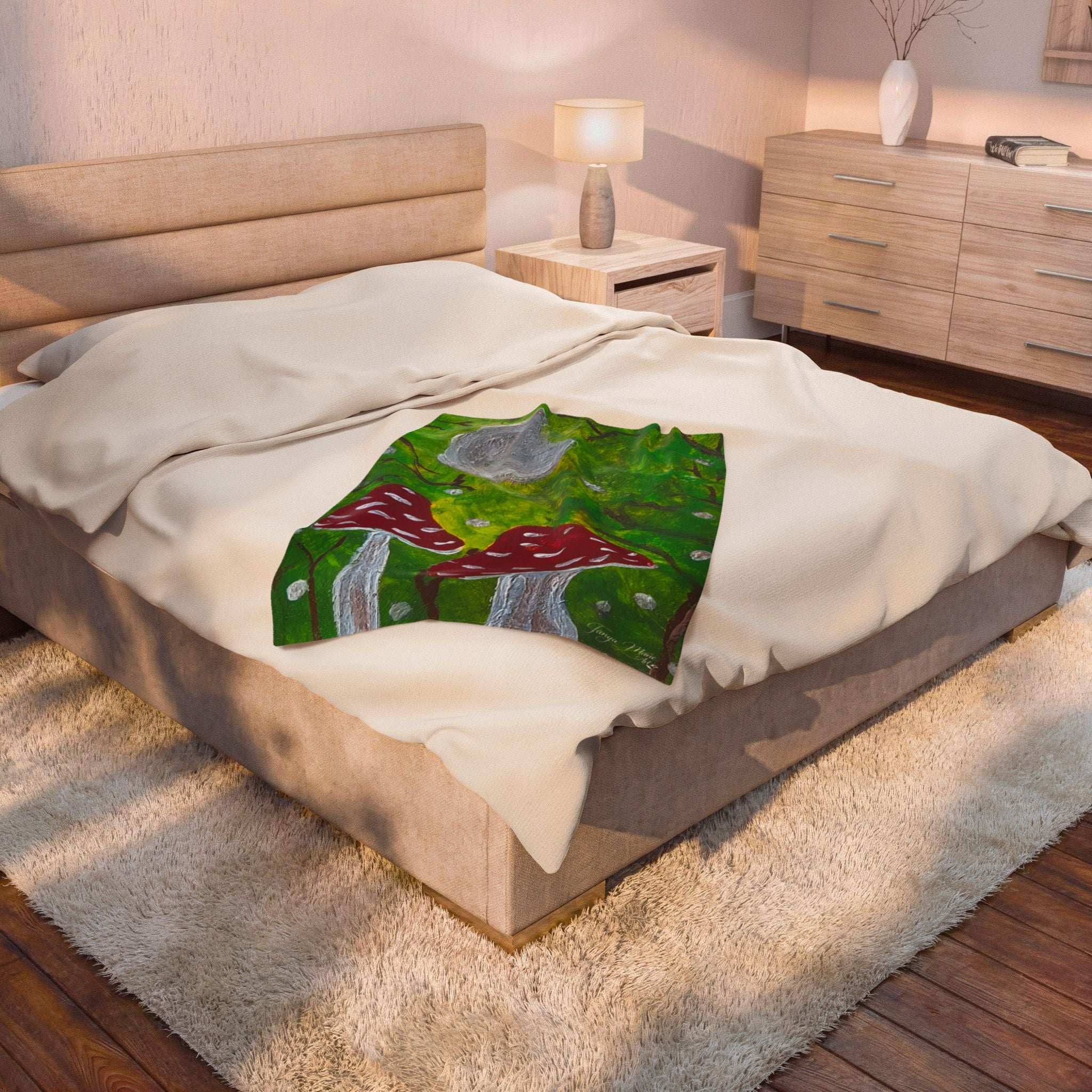 White plush blanket featuring green forest scene with red mushrooms and gray moon detail.
